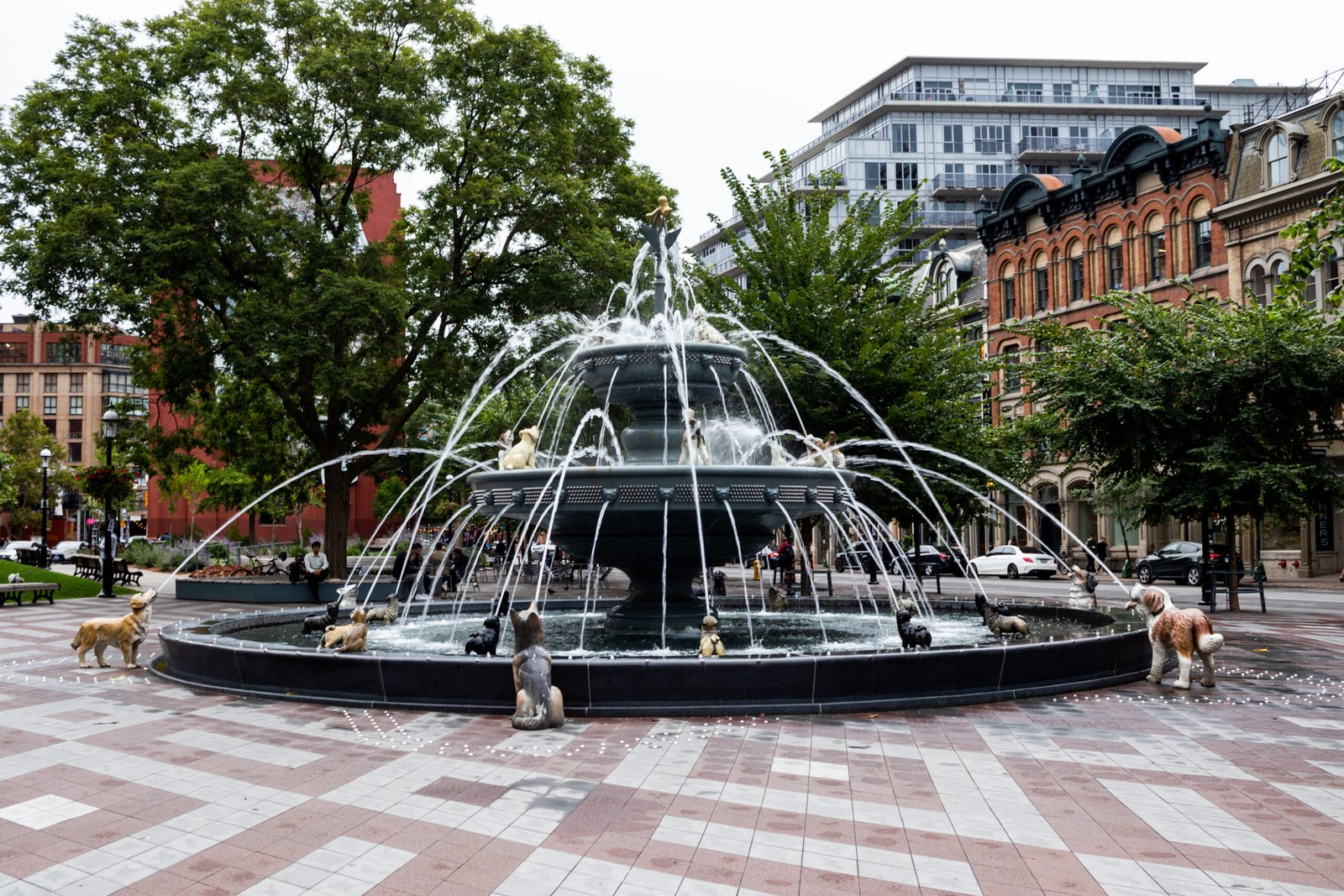 Dog fountain in Berczy Park in Toronto’s St. Lawrence neighborhood with trees, benches, and historic brick buildings