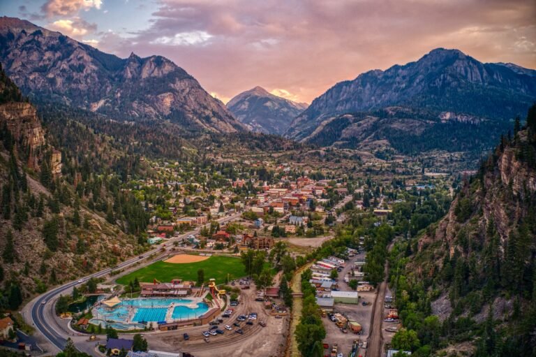 Colorado hot springs town nestled in a mountain valley at sunset with a large outdoor pool in the foreground