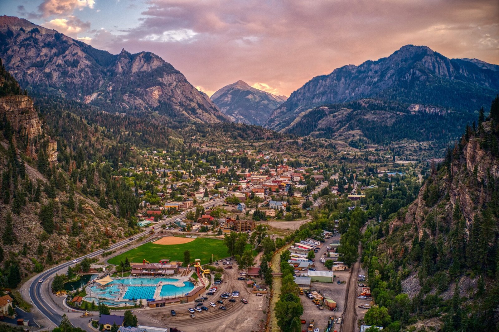 Colorado hot springs town nestled in a mountain valley at sunset with a large outdoor pool in the foreground