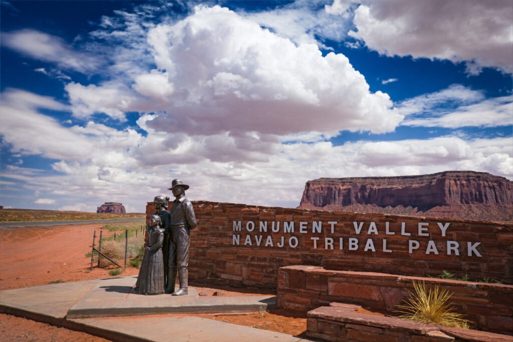 trance sign for Monument Valley Navajo Tribal Park in Arizona, with red rock formations and a dramatic sky in the background.