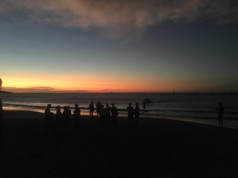 Families gathered on Tamarindo Beach watching a colorful Pacific sunset.