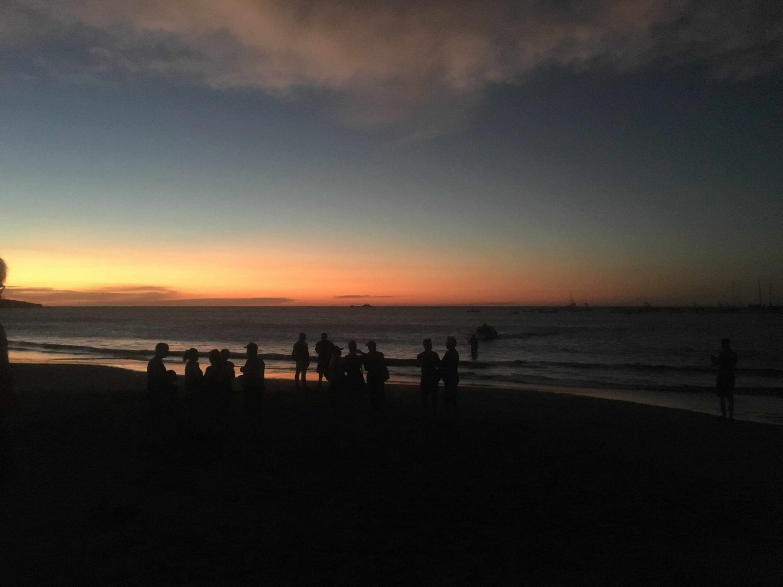 Families gathered on Tamarindo Beach watching a colorful Pacific sunset.