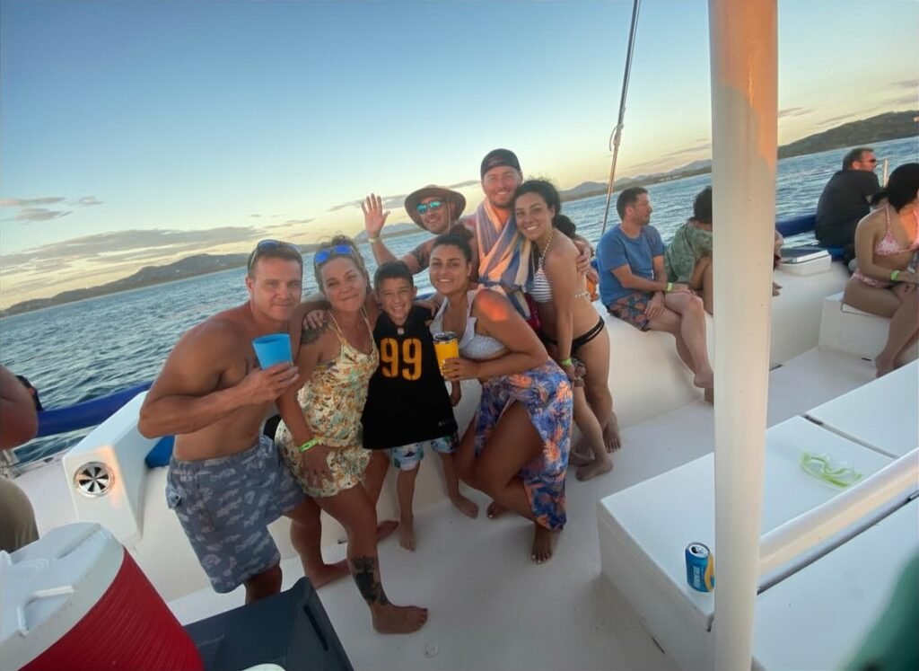 Family relaxing on a catamaran net at sunset off the coast of Tamarindo on Day 6 sailing and snorkeling trip.
