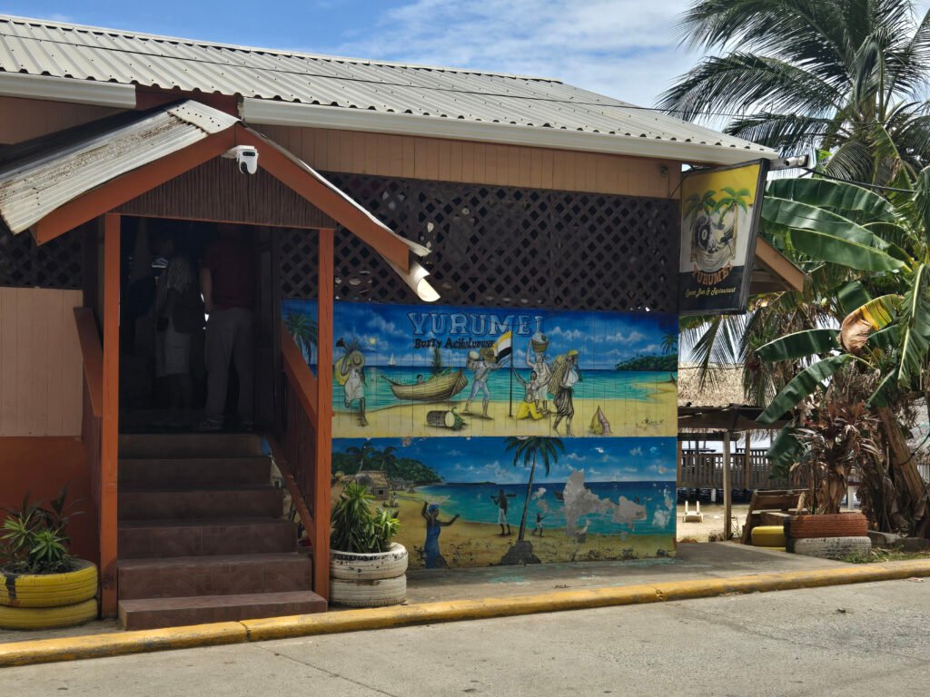 Exterior of Yurumei Restaurant in Punta Gorda, Roatán, with a colorful Garifuna-themed mural facing the street.