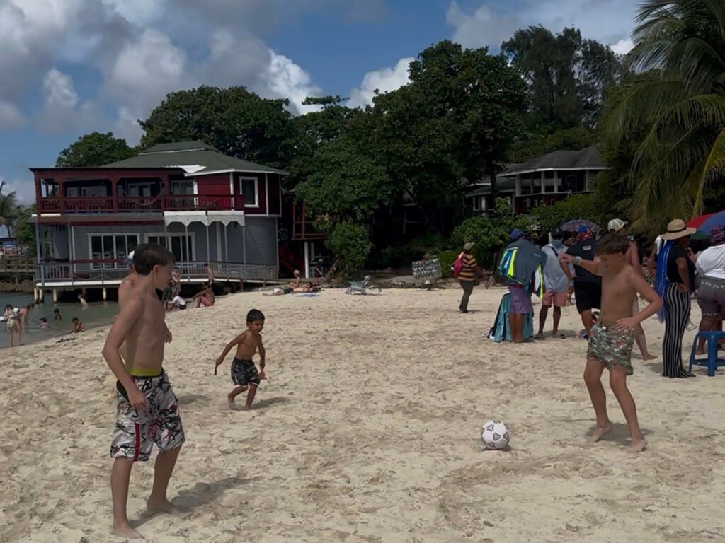 Kids and teens playing soccer on the sand at West Bay Beach in Roatán on a sunny day.