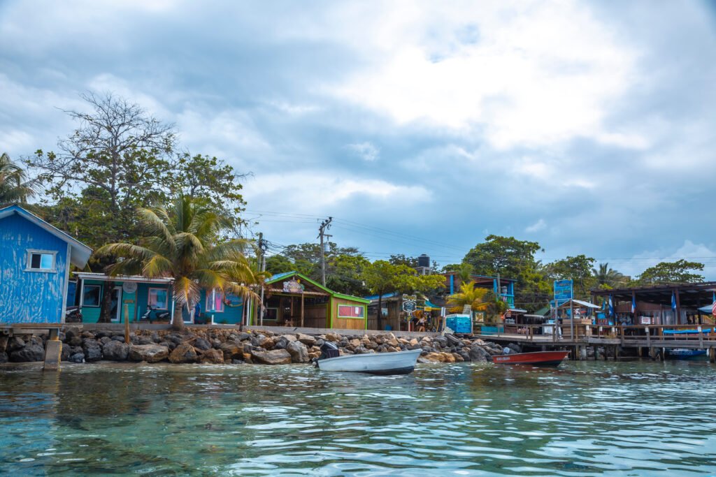 Colorful wooden bars and dive shops along the waterfront in West End, Roatán, seen from the water.
