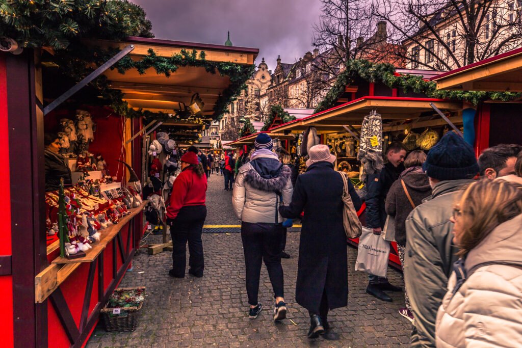 Visitors browse Christmas market stalls decorated with evergreen garlands on Strøget in central Copenhagen, Denmark.