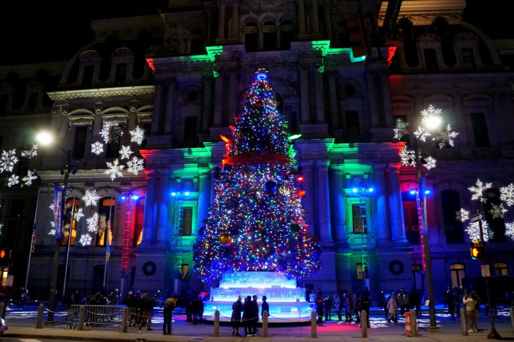 Philadelphia City Hall decorated with a Christmas tree and holiday lights at night.