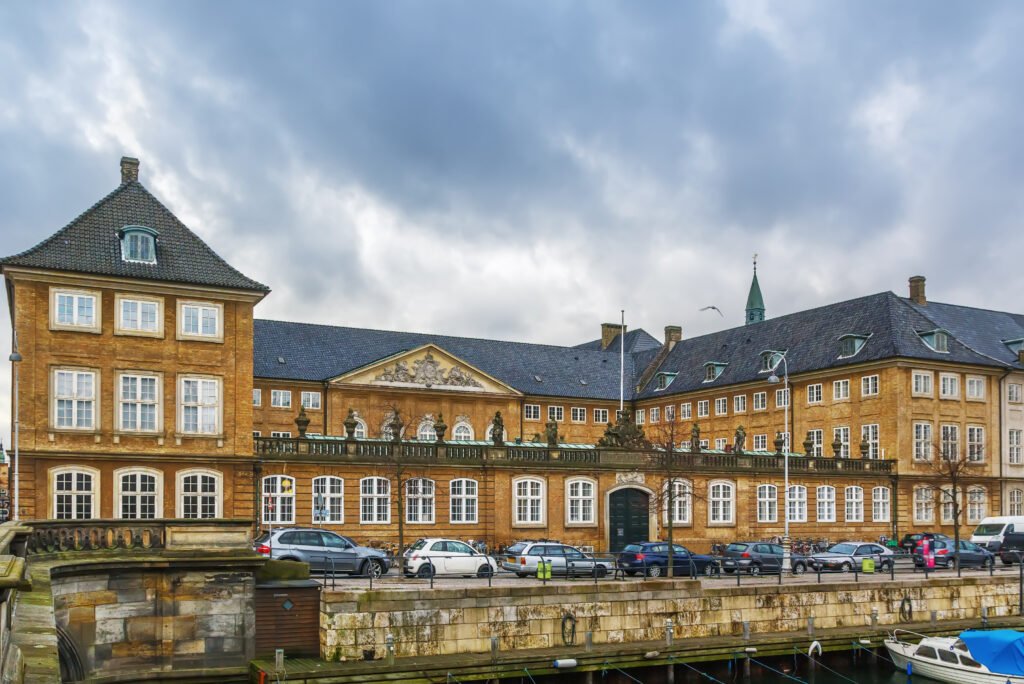 The National Museum of Denmark’s historic yellow-brick building viewed across Frederiksholms Kanal beneath an overcast sky.