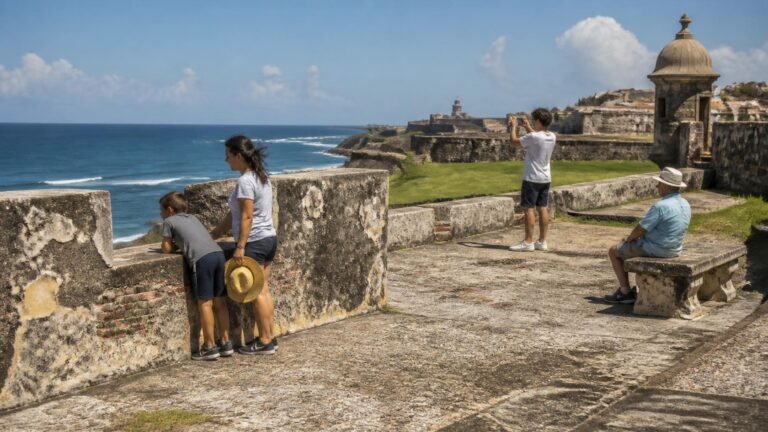 Multigenerational family exploring an oceanfront fort, with a child looking through a stone wall, a teen taking photos, and an older adult resting.